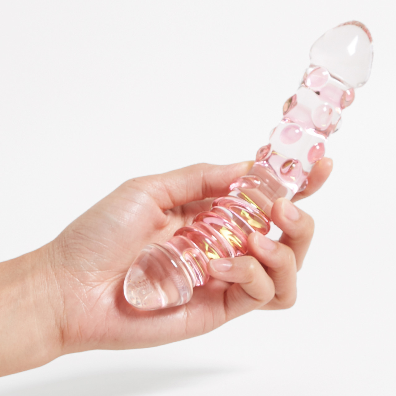 'Glass Dual Curved Wand', a transparent pink glass massager with texture in a hand