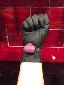 A fist wearing a black nitrile glove and vibrator.