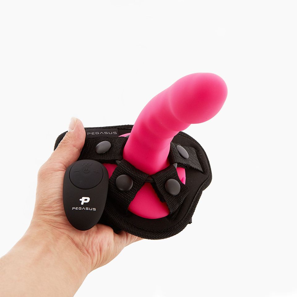 Pegasus Ripple Dildo with Harness, a pink toy attached to a black harness with remote control held in a hand